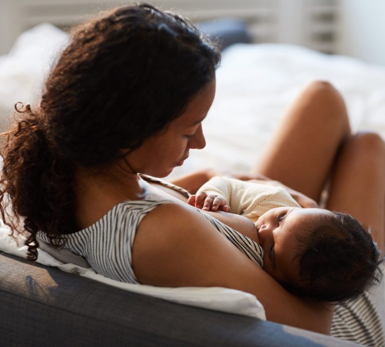 Sage-femme souriante avec une mère et un nouveau-né à l'hôpital dans un cadre lumineux et accueillant.